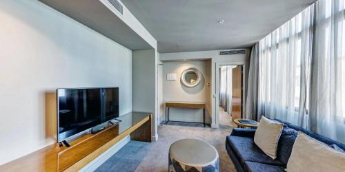 a living room with a couch and a tv at Distinction Dunedin Hotel in Dunedin