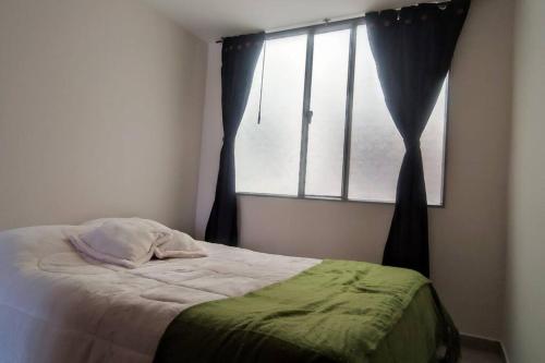 a bed in a room with a window and a bedspread at Acogedor y Luminoso apartamento in Tunja