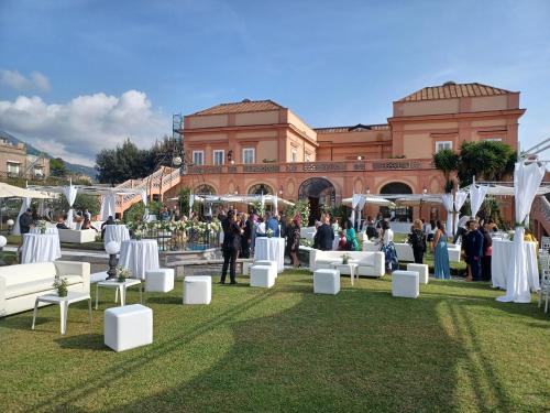 a group of white chairs on the grass in front of a building at Villa Signorini Hotel in Ercolano