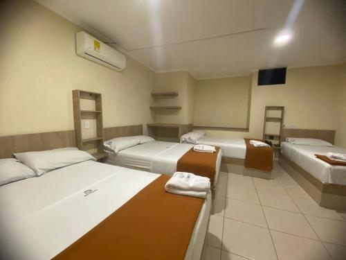 a room with three beds in a room at Hotel Ruiseñor Itagui in Itagüí