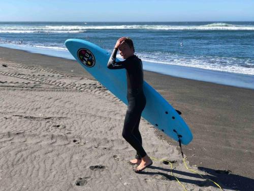 a woman standing on the beach holding a surfboard at Duerme y despierta en el Mar in Curanipe