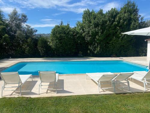 a pool with chairs and an umbrella next to it at casa dos esteios in Penafiel