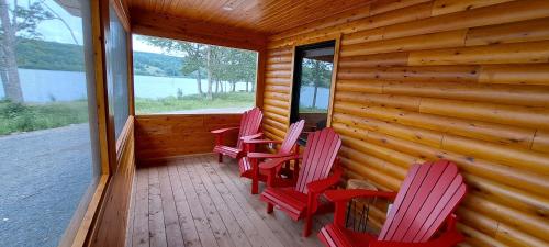 a porch with red chairs on a log cabin at Lochaber Homesteader Lodge in Antigonish