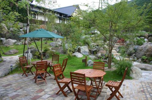 un patio con mesas, sillas y una sombrilla en Tomarudake Nozawa en Hitoegane