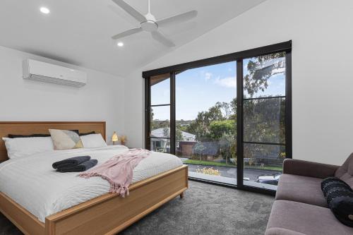 een slaapkamer met een bed en een groot raam bij Luxurious Haven House by the Beachside Ocean Grove in Ocean Grove