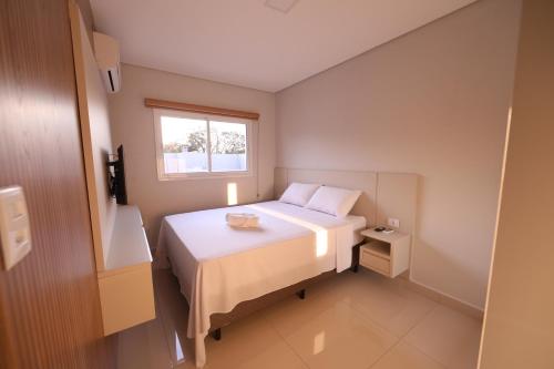 Un pequeño dormitorio con una cama blanca y una ventana en Apartamento Espaço Aconchegante, en Foz do Iguaçu