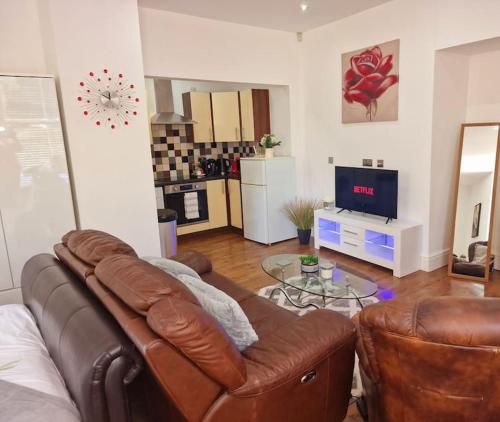 a living room with a leather couch and a television at The Cosy Corner studio in Sheffield