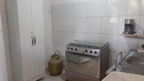a white tiled kitchen with a stove and a sink at Lar sossego in Itabuna