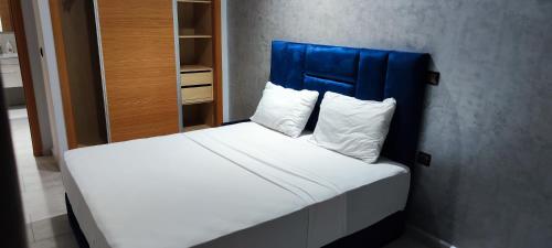 a bed with a blue headboard and white pillows at Les Belles Appartements Family Only in Tangier