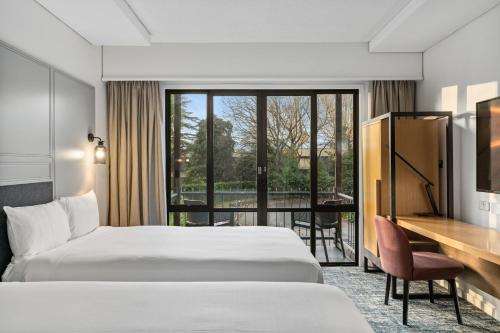 a hotel room with two beds and a desk at Chateau On The Park - Christchurch, A Doubletree By Hilton in Christchurch