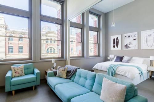 a living room with a couch and a bed and windows at Inspiration Station - An Iconic Designer Pad in Melbourne