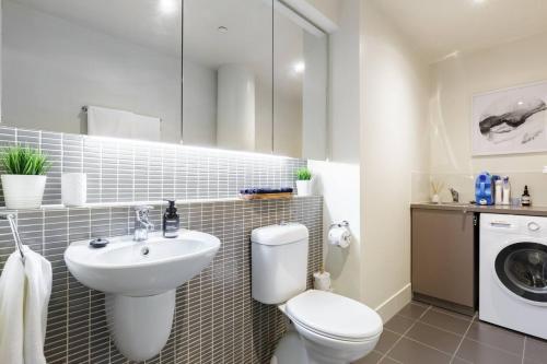 a bathroom with a toilet and a sink and a washing machine at Inspiration Station - An Iconic Designer Pad in Melbourne