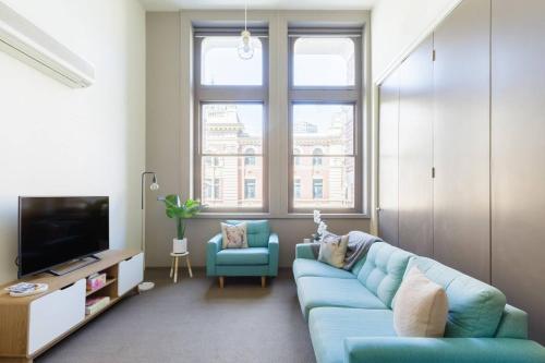 a living room with a blue couch and a tv at Inspiration Station - An Iconic Designer Pad in Melbourne
