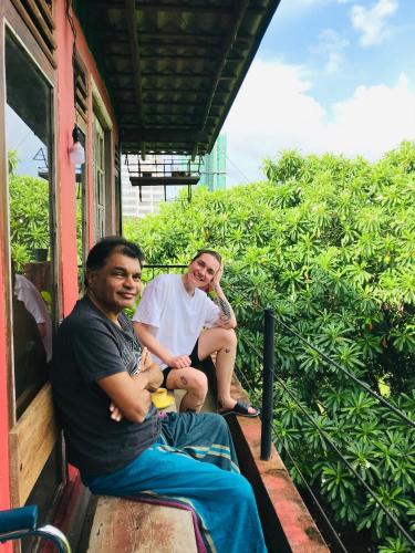 two people sitting on a porch of a house at Coca Cola Hostel Malabe in Malabe