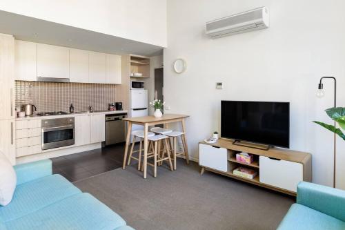 a living room with a couch and a kitchen with a tv at Inspiration Station - An Iconic Designer Pad in Melbourne