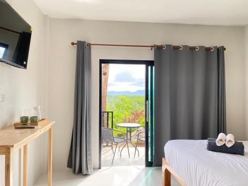 a bedroom with a bed and a sliding glass door at De Saran Lanta in Ko Lanta