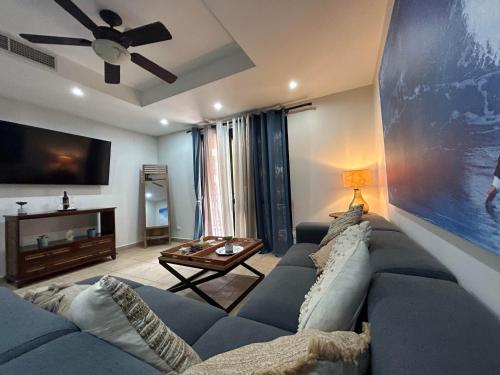 sala de estar con sofá azul y TV en Apartamento de lujo frente a playa Jacó-3 BD/ 2 BA, en Jacó