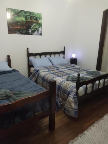 a bedroom with two beds and a painting on the wall at Pousada Canto do Sertão in São Miguel Arcanjo