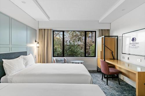 a hotel room with two beds and a desk at Chateau On The Park - Christchurch, A Doubletree By Hilton in Christchurch