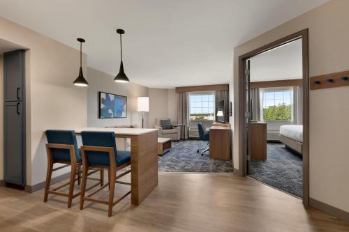 a room with a desk and chairs and a bedroom at Candlewood Suites San Antonio Downtown by IHG in San Antonio