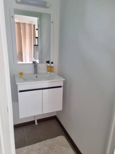 a white bathroom with a sink and a mirror at Bungalow Moorea à 50 mètres du lagon in Farehau
