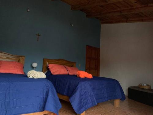 a bedroom with two beds and a cross on the wall at Casa Brisa in Tapalpa