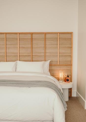 a bedroom with a white bed with a wooden headboard at The Oak & Anchor Hotel in Port Fairy