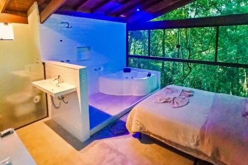 a bathroom with a bed and a tub and a sink at Refúgio na Serrinha do Alambari - Penedo -RJ in Resende