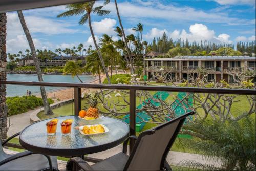 a table with food on a balcony with a view of a resort at The Mauian Hotel in Lahaina