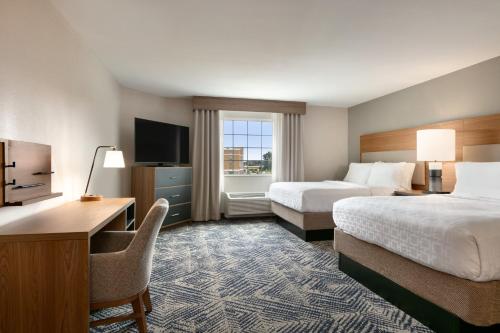 カンザスシティにあるCandlewood Suites Kansas City Northeast, an IHG Hotelのベッド2台、デスク、テレビが備わるホテルルームです。