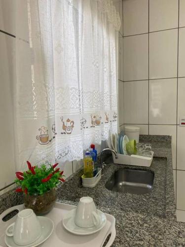 encimera de cocina con vajilla, fregadero y fregadero en apartamento inteiro en Cuiabá