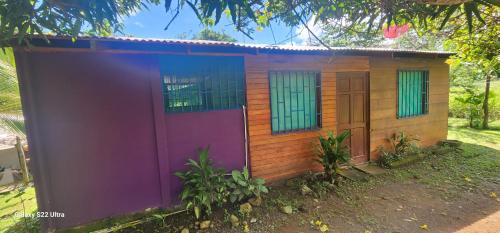 una pequeña casa pintada de color púrpura y verde en Refugio Valverde Alonso, en Puerto Jiménez