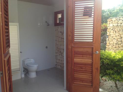 a bathroom with a toilet and a wooden door at Casa 01 in Cabrera