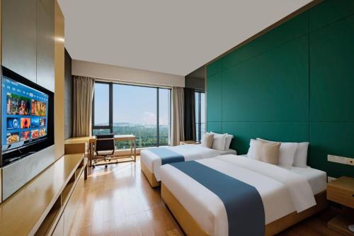 two beds in a hotel room with a flat screen tv at eStay Residence·Poly World Trade Center Guangzhou in Guangzhou