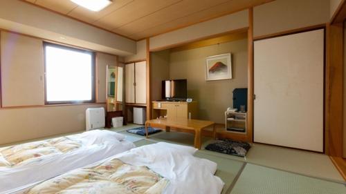 a bedroom with a bed and a desk and a window at Onomichi Kokusai Hotel in Onomichi