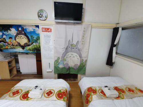 Habitación con 2 camas y TV en la pared. en totoro house, en Musashino