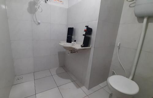a white bathroom with a toilet and a sink at Casa Viçosa 5km centro in Viçosa do Ceará