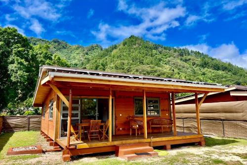 uma pequena cabana de madeira com uma montanha ao fundo em Fare Te Ava - Comfy cabin w Private Beach Access em Haapiti