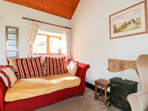 ein Wohnzimmer mit einem roten Sofa und einem Fenster in der Unterkunft Manifold Cottage in Grindon