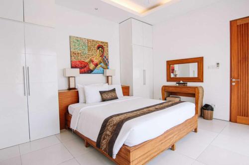 - une chambre blanche avec un grand lit et un miroir dans l'établissement Bali Easy Living Canggu, à Canggu