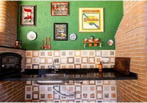 a kitchen with a sink and a brick wall at Recanto Mona Paraiso no Centro da Cidade. in Pindamonhangaba