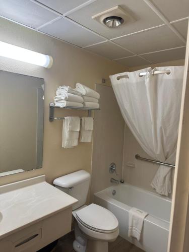 a bathroom with a toilet and a sink and a tub at Big Bend Traveler's Inn in Great Bend
