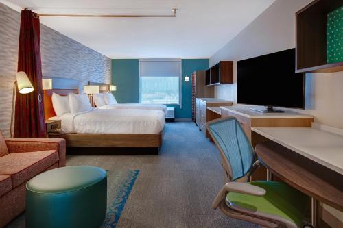 ガーデングローブにあるHome2 Suites By Hilton Garden Groveのベッドとテレビが備わるホテルルームです。