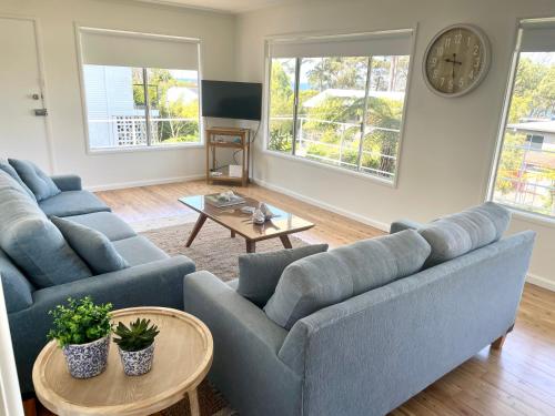 a living room with two blue couches and a table at 3 Beaches Cottage in Surf Beach