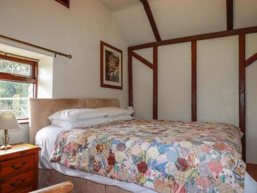 a bedroom with a bed with a quilt on it at Jolls Ground Barn in Altarnun