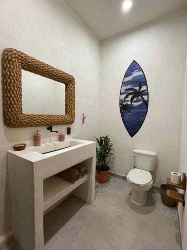 een badkamer met een wastafel en een spiegel en een toilet bij Hostel Flakos in Zihuatanejo