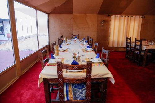 ein Esszimmer mit Tischen und Stühlen und einem großen Fenster in der Unterkunft Luxury berber style in Merzouga