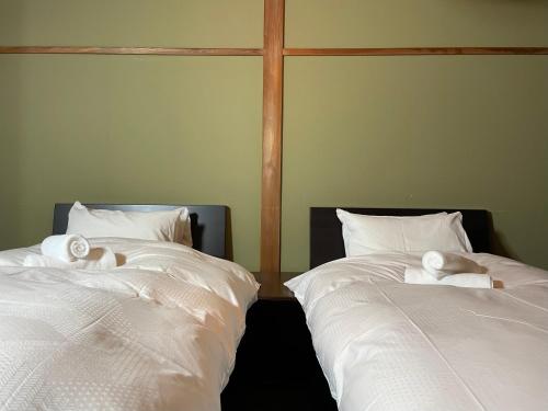 two beds sitting next to each other with white sheets at A short walk to Akakura Onsen Ski Lift and Town by Japow House in Myoko