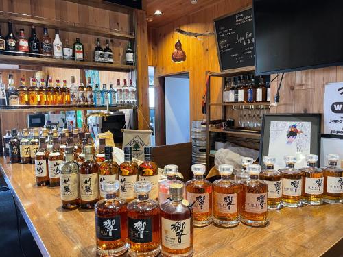un montón de botellas de whisky sentadas en un bar en Japow House en Myoko
