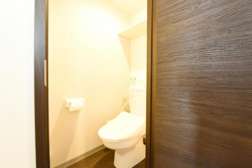 a bathroom with a toilet and a wooden door at Sun Court Hondori Garden Hills in Tsukisappu